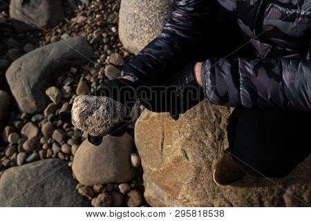 Young Archaeologist On A Boulder Beach Looking For Exotic Rocks On A Coastline Of A Baltic Sea