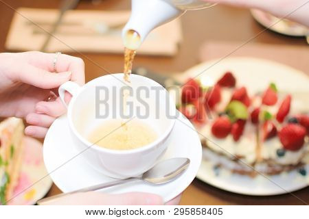 Tea Party. Women Pour Green Tea Into A White Cup