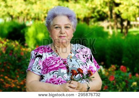 Elderly Woman On A Background Of Park Vegetation On A Summer Day