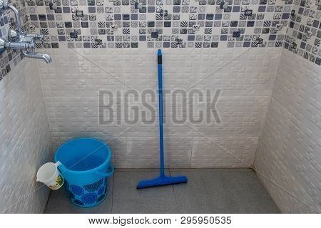 Blue Bucket With Mug And Wipper Lying In Bathroom