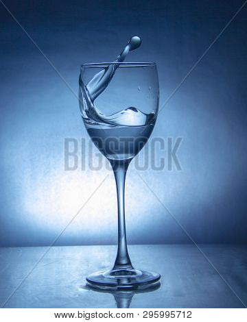 Splash Of The Drink In The Glass On The High Leg On Colored Background