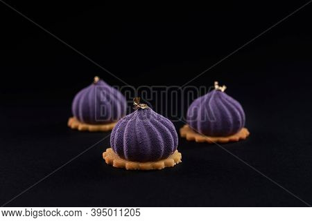 Closeup View Of Matte Purple Dessert In Fig Shape Isolated On Black Studio Background. Three Small S