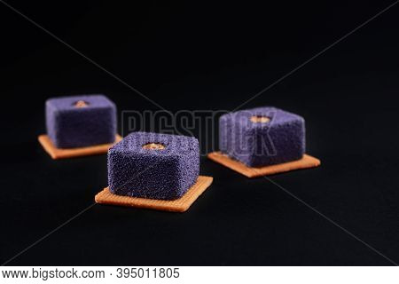 Purple Matte Purple Dessert Filled With Brown Creme Isolated On Black Studio Background. Closeup Vie