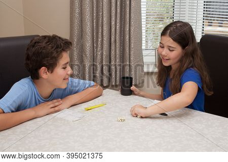 Wool, Dorset, Uk 08 13 2020 A Brother And Sister Playing A Game Of Yahtzee On A Dinning Room Table, 