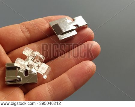 A Set Of Feet For An Electric Sewing Machine In A Female Hand. Gray Backdrop. Standard Sewing Or Zig