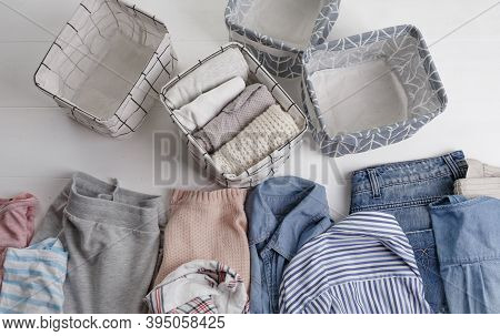 A Group Of Organic Cotton Clothing Set On A White Table Is Ready To Be Folded Into White Baskets.the