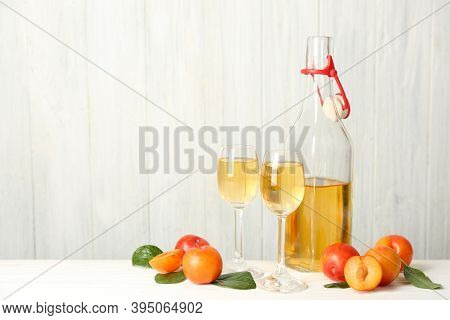 Delicious Plum Liquor And Ripe Fruits On White Wooden Table, Space For Text. Homemade Strong Alcohol