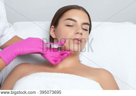 Cosmetologist Makes Lipolytic Injections To Burn Fat On The Chin, Cheeks And Neck Of A Woman Against
