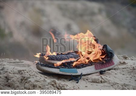 Burning Sports Sneakers Or Gym Shoes On Fire Stand On Sandy Beach Coast. Athlete Burned Out. Physica