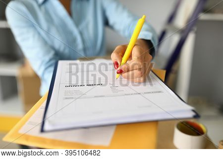 Close-up Of Woman Filling Delivery Receipt Document. Female With Nice Red Manicure Holding Yellow Pe