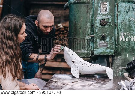 People Carefully Work On A Ceramic Whale In Workshop