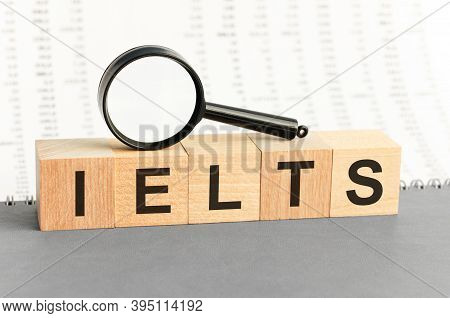 On Wooden Blocks Under A Magnifying Glass Text: Ielts. Educational Concept. Ielts - Words From Woode