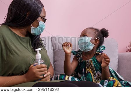 African Americans' Mother And Daughter Wearing A Mask Are Washing Their Hands With Alcohol To Protec