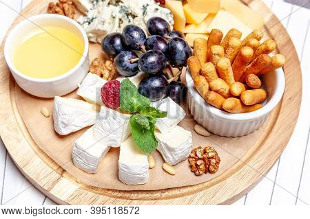 Board With Different Types Of Cheese. Cheeses Mix Set Dor Blu Chedar Parmesan Brie Honey Sauce Finge