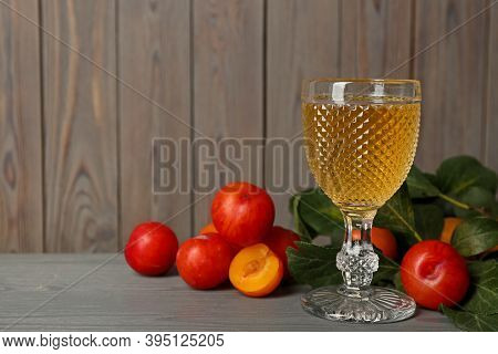 Delicious Plum Liquor And Ripe Fruits On Grey Wooden Table, Space For Text. Homemade Strong Alcoholi