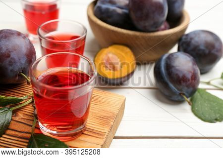 Delicious Plum Liquor And Ripe Fruits On White Wooden Table, Closeup. Homemade Strong Alcoholic Beve
