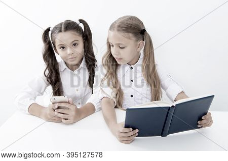 Innovation And Archaism Concept. Children Read Paper Book And Electronic Mobile Device Using Innovat
