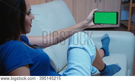 Caucasian Woman In Pijamas Looking At Smart Phone With Green Screen. Lady Holding A Mobile Phone Wit