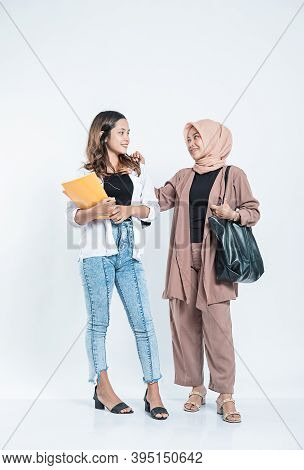 Portrait Of A Young Woman Smiling Meeting A Study Friend Carrying A Bag And Book