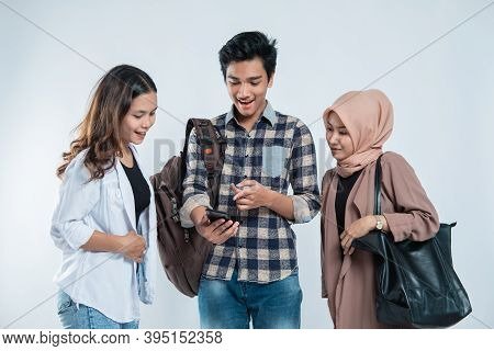 Portrait Of Happy University Youth Carrying Bags And Discussion Looking At Cell Phones
