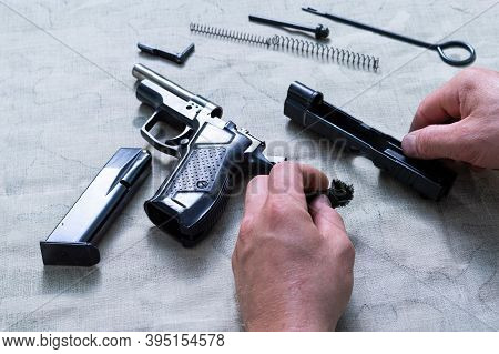 Details Of The Disassembled Pistol. The Hands Of The Master Hold The Frame Of The Pistol.