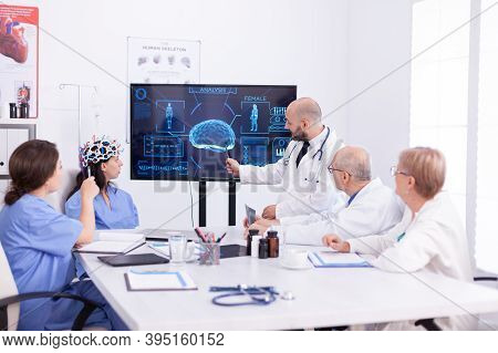 Doctor Talking About Brain Activity During Conference With Medical Staff And Nurse Wearing Headset W