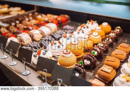 Different Types Of Small Cakes In Candy Store Behind Glass Display