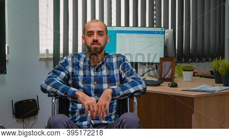 Handicapped Disabled Businessman In Wheelchair Waving At Videocall Having Online Conference In Busin