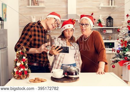Niece Celebrating Christmas With Grandparent Making Funny Faces While Taking Selfies. Happy Cheerful