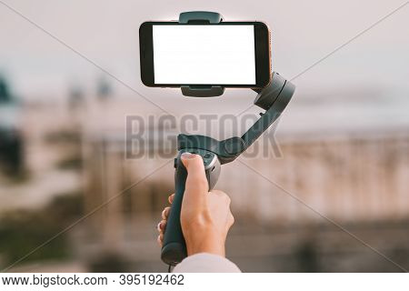 Woman Hand With A Gimbal For Smartphone With Blank Screen. Vlog And Video Blogging Concept.
