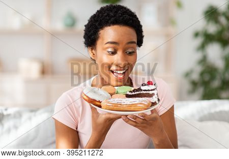Diet Breakdown And Unhealthy Nutrition Concept. Young African American Lady Holding Plate Of Sweet P