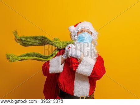 Merry Christmas and Happy Holidays! Santa Claus in face mask on bright color background. Covid-2019