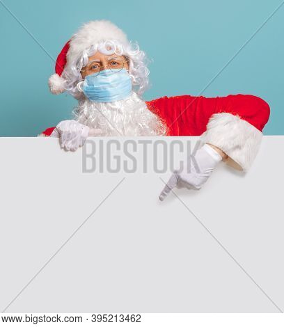 Merry Christmas and Happy Holidays! Santa Claus in face mask on bright color background. Covid-2019