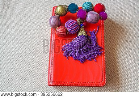 Little Red Book With Beads On The Table .