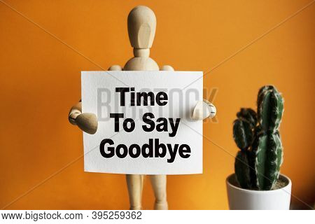 The Wooden Man Holds A White Sign With The Text Time To Say Goodbye In His Hands. The Content Of The