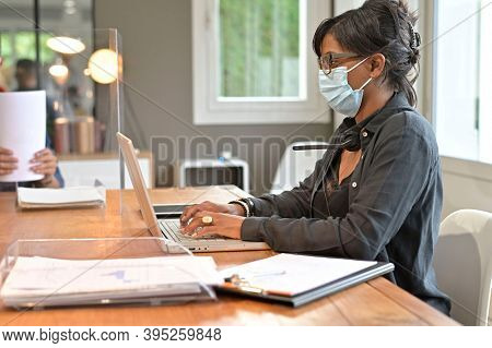 Office worker wearing surgical face mask in open space area
