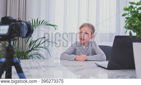 Child blogger videotapes his vlog at home. Boy recording his video blog. White boy speaks in front of a video camera for his blog channel. Little 8 year vlogger makes online streaming using smartphone