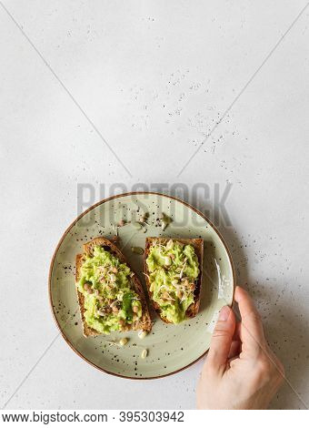 Female Hand Hold A Green Plate Withy Avocado Toasts With Sprouts And Various Seeds. Top View. Copy S