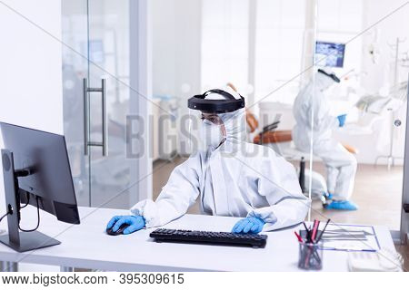 Nurse Using Computer During Covid 19 Wearing Ppe Suit As Safety Precaution. Medicine Team Wearing Pr