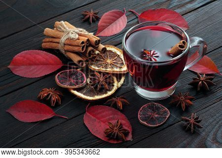 Cup Of Mulled Wine, Spices And Red Autumn Leaves On A Wooden Table