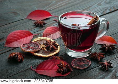 Cup Of Mulled Wine, Spices And Red Autumn Leaves On A Wooden Table