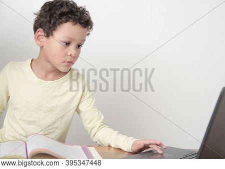 Boy With Book At A Table After Going Back To School On White Background Stock Photo