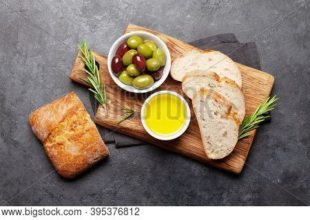 Ripe olives, olive oil and ciabatta bread. Top view flat lay
