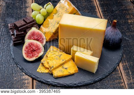 British Matured Yellow Cheese Blue Shropshire, Smoked Cheddar And Fresh Figs Close Up On Black Stone