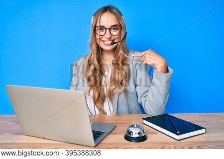 Young beautiful blonde woman wearing operator headset at the call center office pointing finger to one self smiling happy and proud 