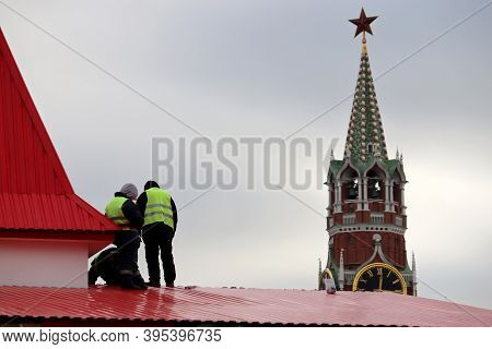 Builders Working On A Roof On Moscow Kremlin Tower Background, Selective Focus. Construction And Rep