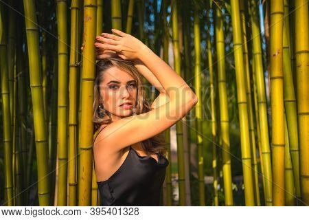 Lifestyle, Blonde Caucasian Girl In A Black Strappy Dress, In A Beautiful Bamboo In The Park Outdoor