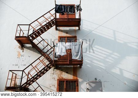 Slums, Sleeping Area. Facade Of A Building With A Rusty Fire Escape And Linen. Poverty Concept, Chea