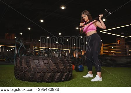 Full Length Shot Of A Plus Size Young Sportswoman Hitting Huge Wheel Tire With A Sledgehammer, Copy 