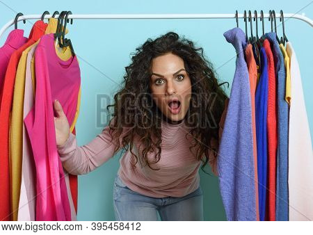 Woman With Surprised Expression Chooses The Clothes To Buy In A Store. Concept Of Shopping And Shopa